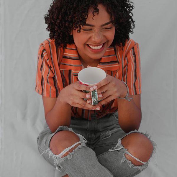 Person smiling peacefully while sitting in a comfortable cross-legged position.